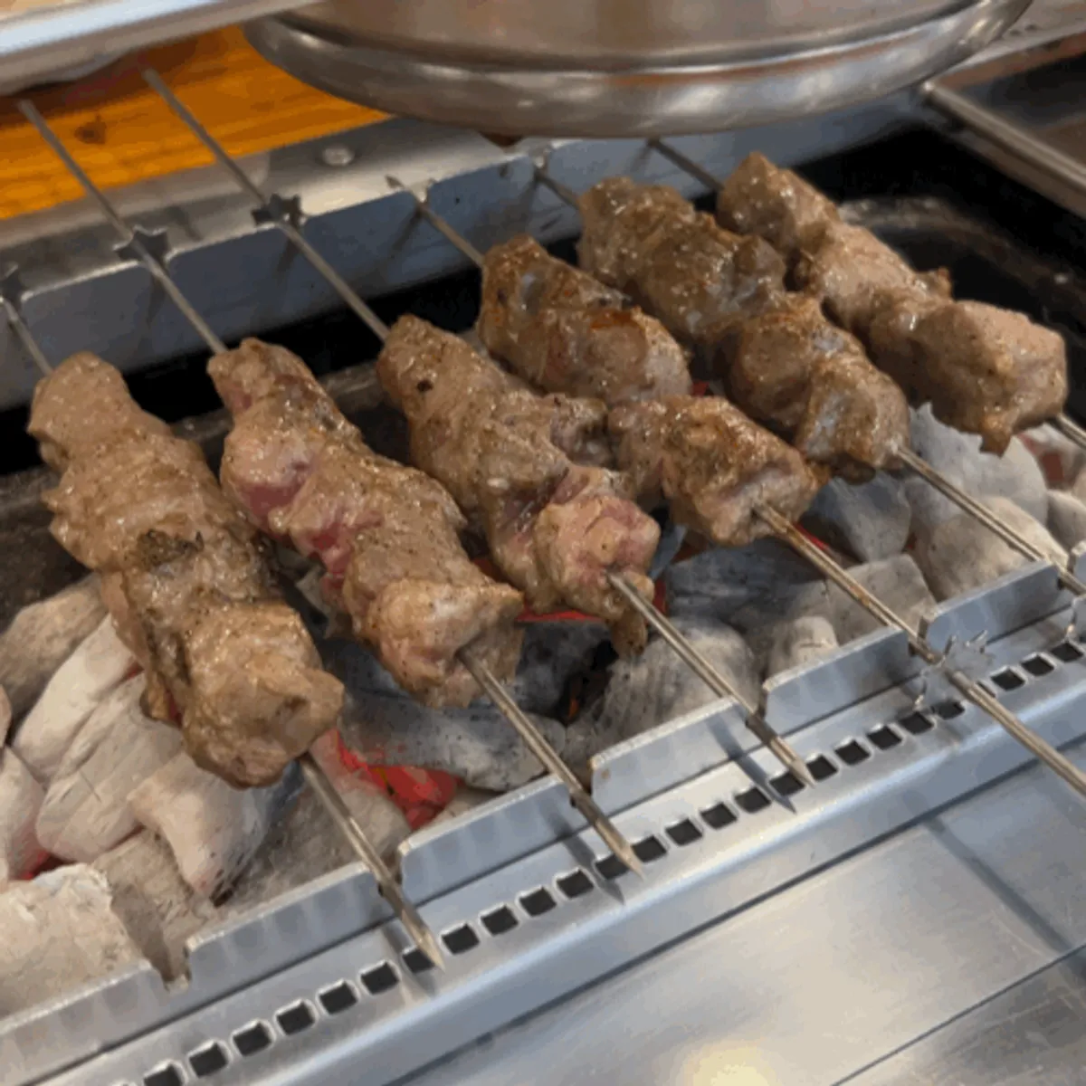 Smoke rising from lamb skewers over the charcoal fire
