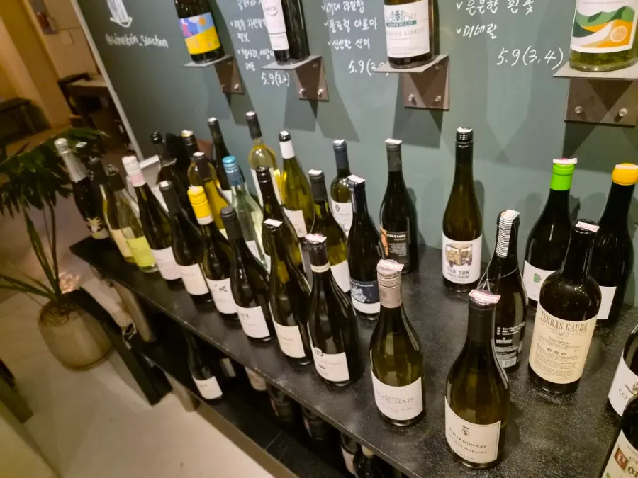 Lower shelf of wines with prices written on the caps
