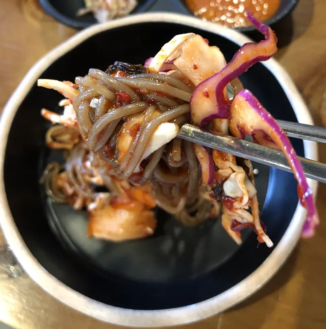Makguksu topped generously with vegetables