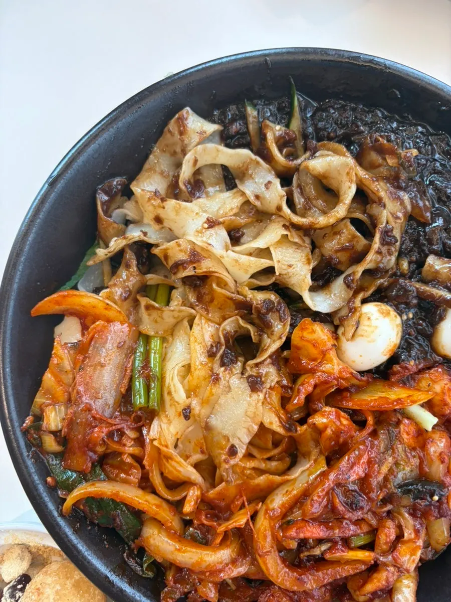 Mixing thick, wide dosakmyeon noodles into the jjajang sauce