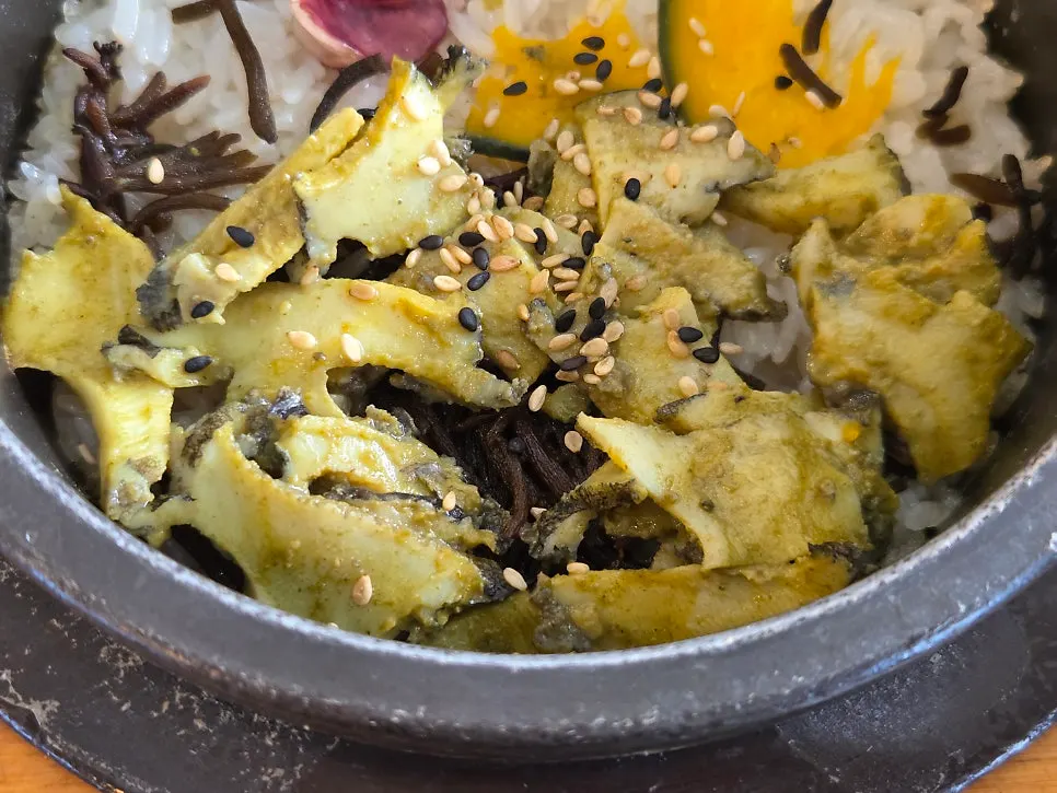 Stone-pot rice topped with abalone slices and sesame seeds