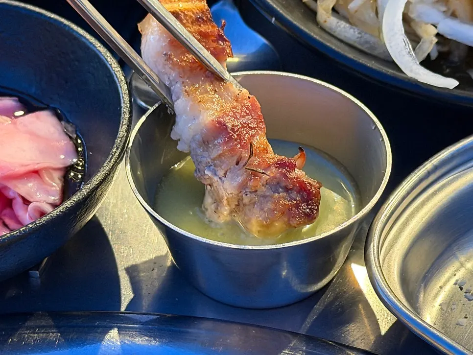 A piece of black pork dipped in wasabi sauce