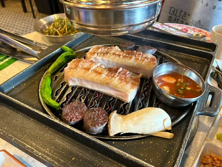 불판 위에서 구워지는 두툼한 흑돼지 오겹살