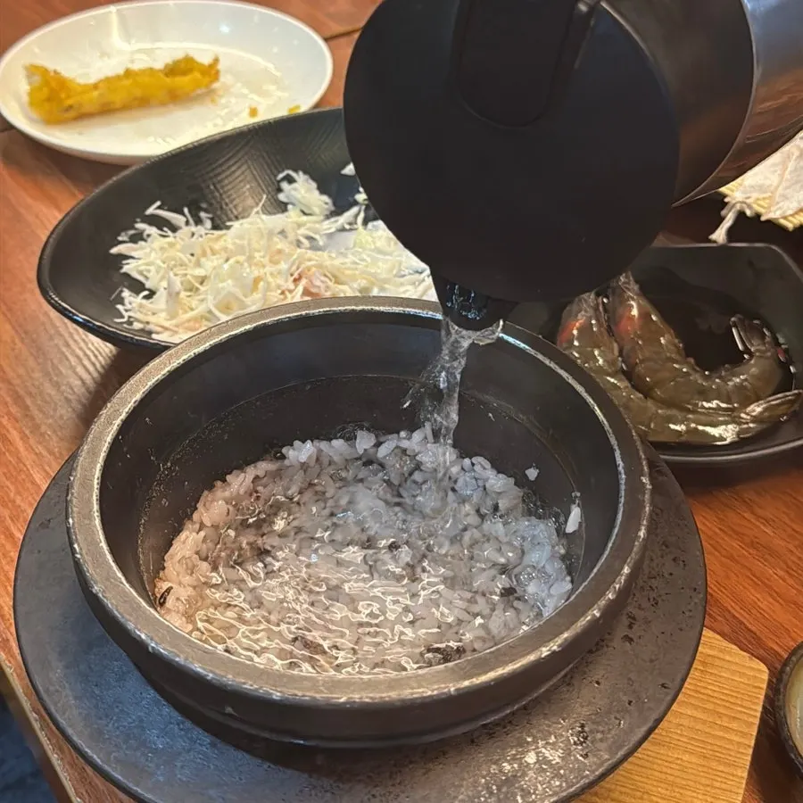 Rice scooped into a bowl with water added to the stone pot