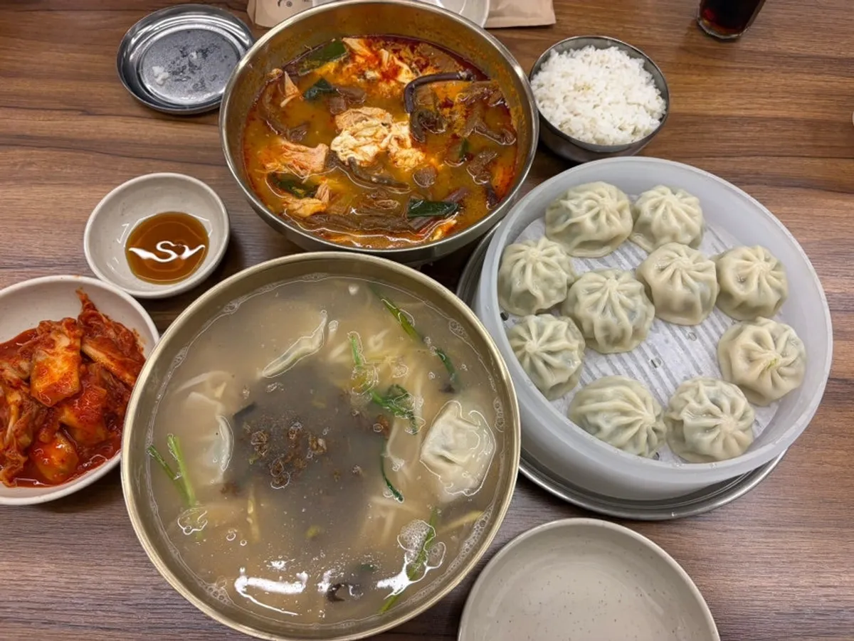 A table set with kalguksu, dakgaejang, and gyoza dumplings