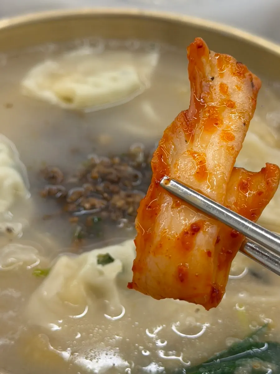 칼국수 면 위에 올린 김치 한 점