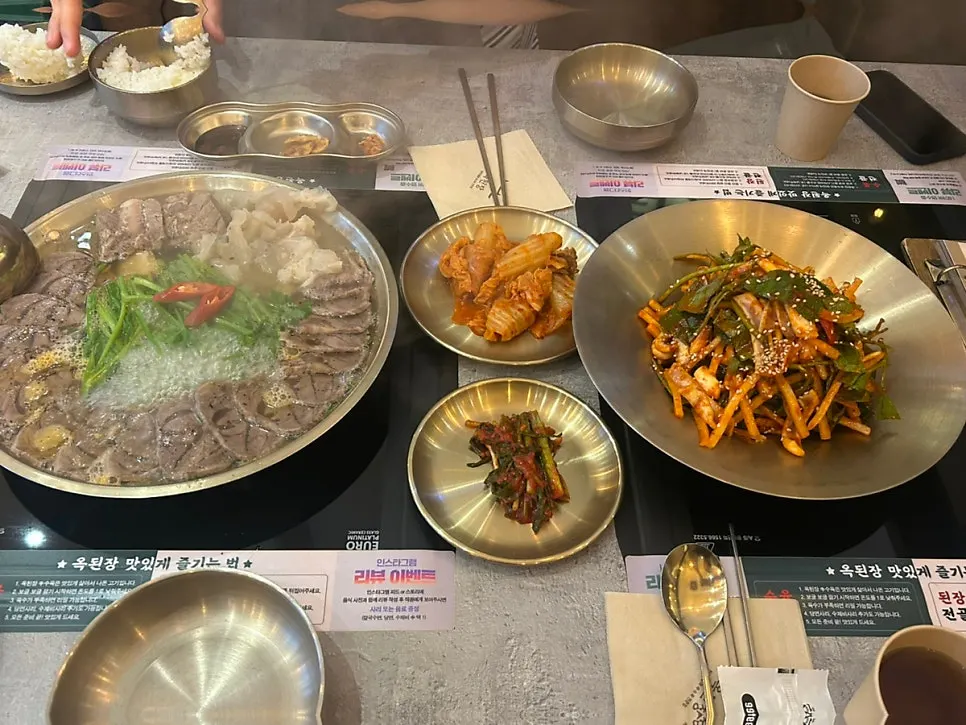 Table spread with boiled pork hot pot, salad and kimchi side dishes