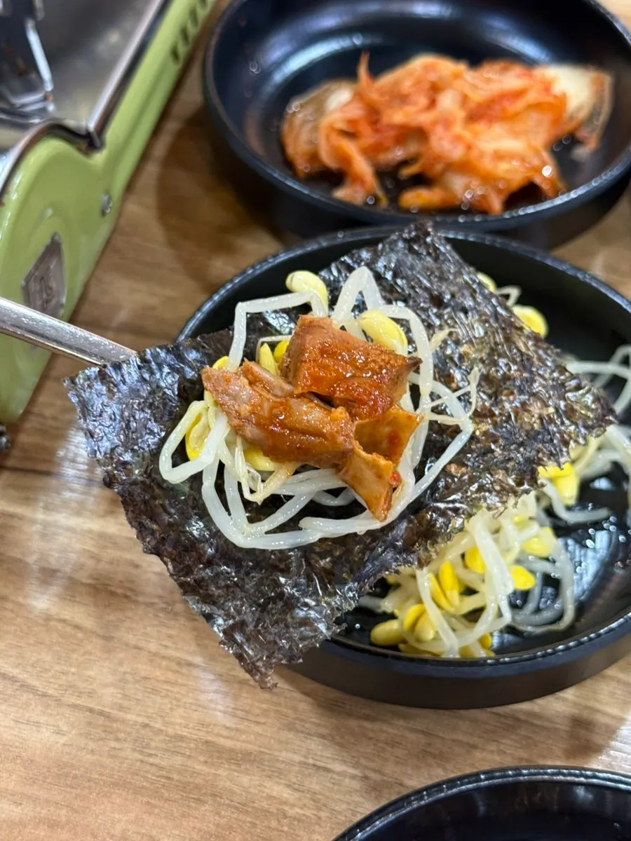김에 콩나물과 갈비찜을 얹어 싸 먹는 모습