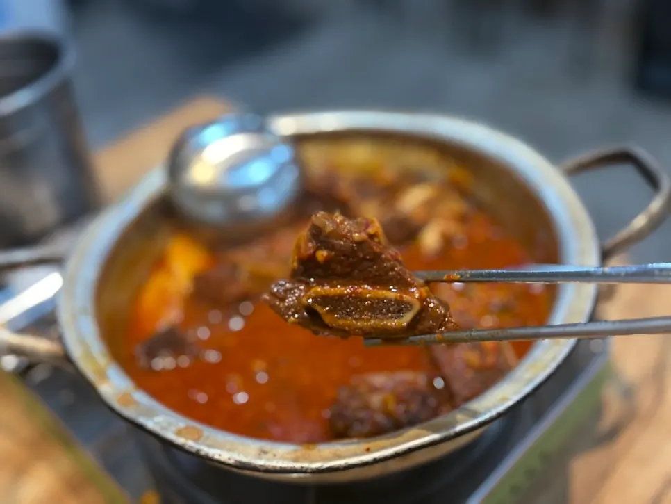 Rib meat separating from the bone, lifted with tongs