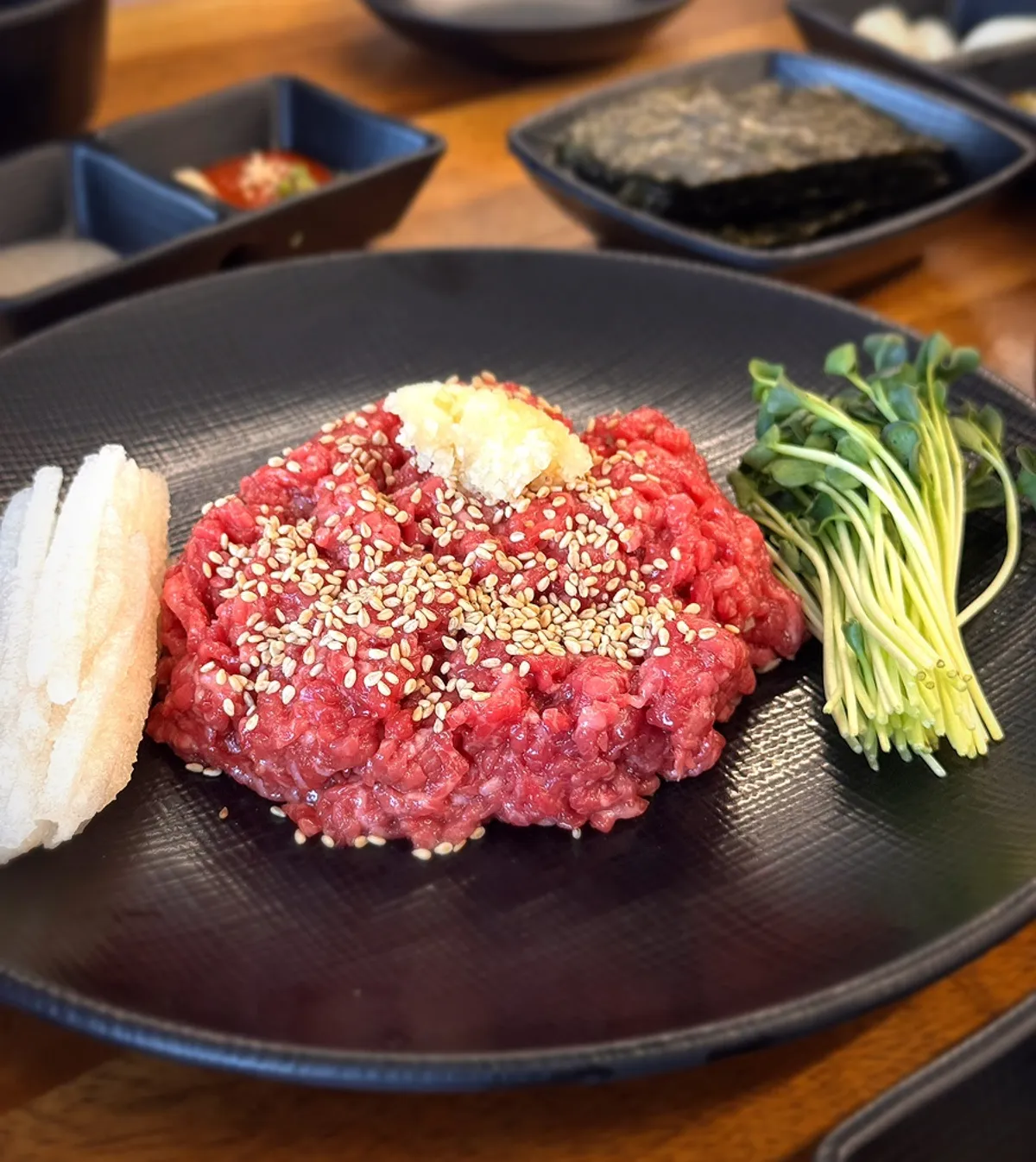 A plate of hanwoo yukhoe with julienned pear and sprouts