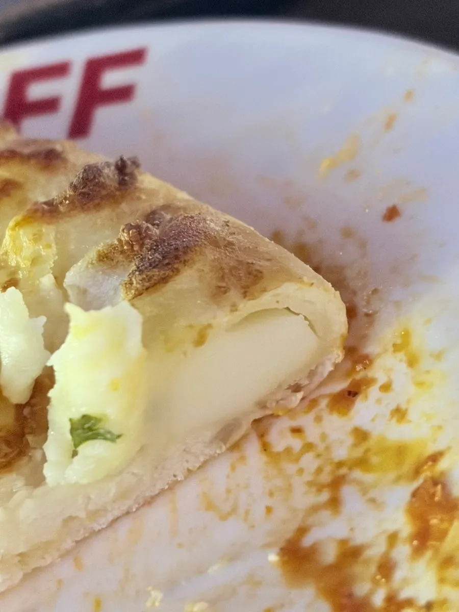 A slice of pizza with stretchy melted cheese