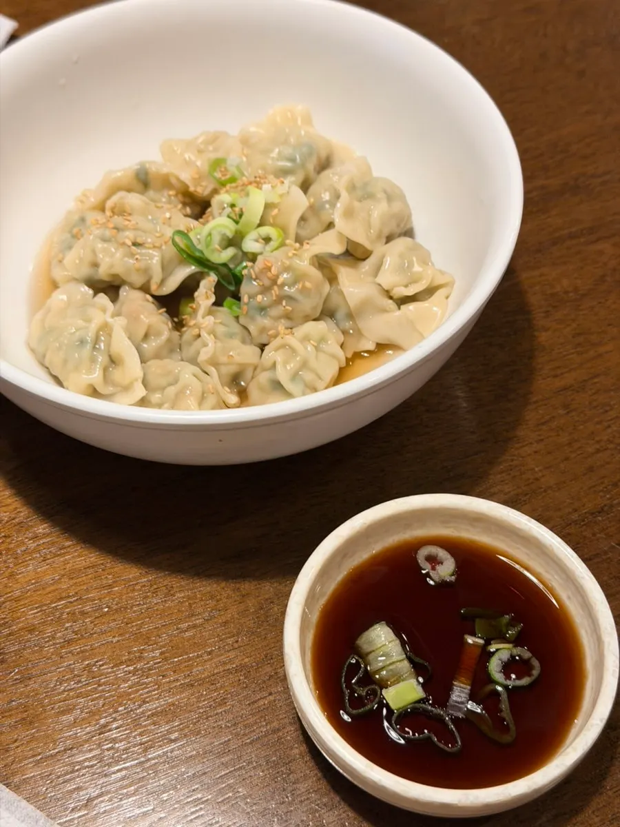 Table spread of fish cake udon, charcoal-grilled squid rice bowl, and dumplings
