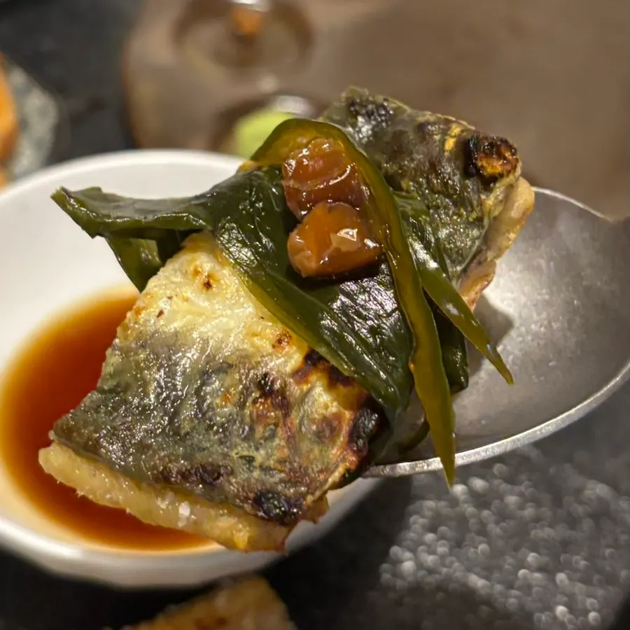 A piece of grilled eel topped with shredded ginger and pickled ginger