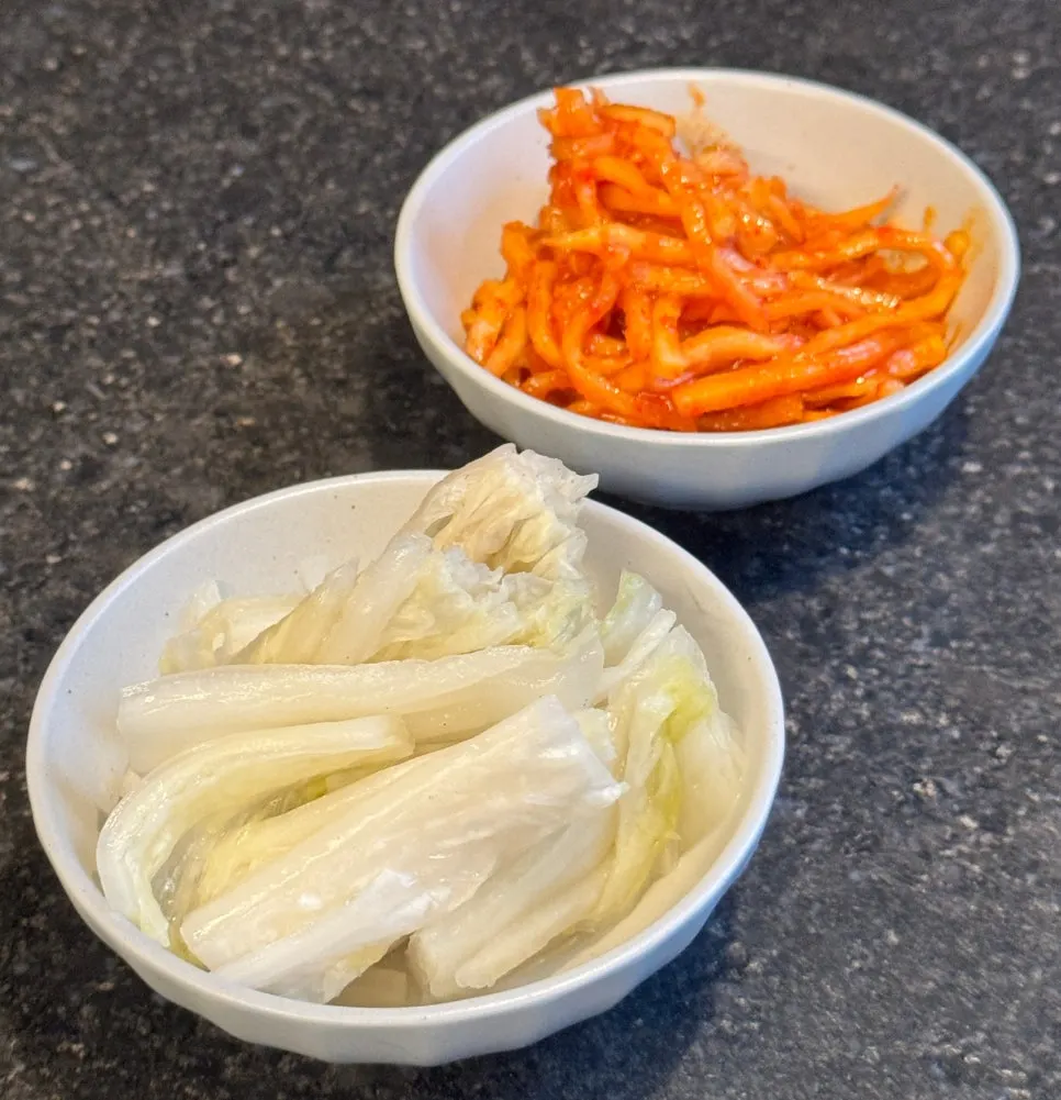 The eel rice bowl spread with white kimchi and radish salad on the side