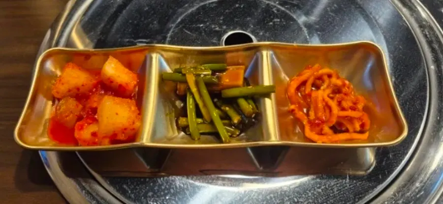 Self-serve banchan on a brass-look three-compartment plate