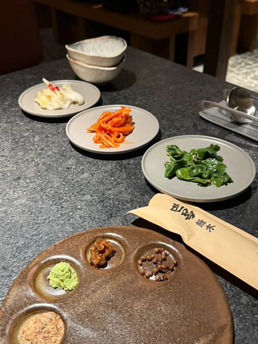 Satu set banchan dasar seperti salad lobak dan kimchi putih