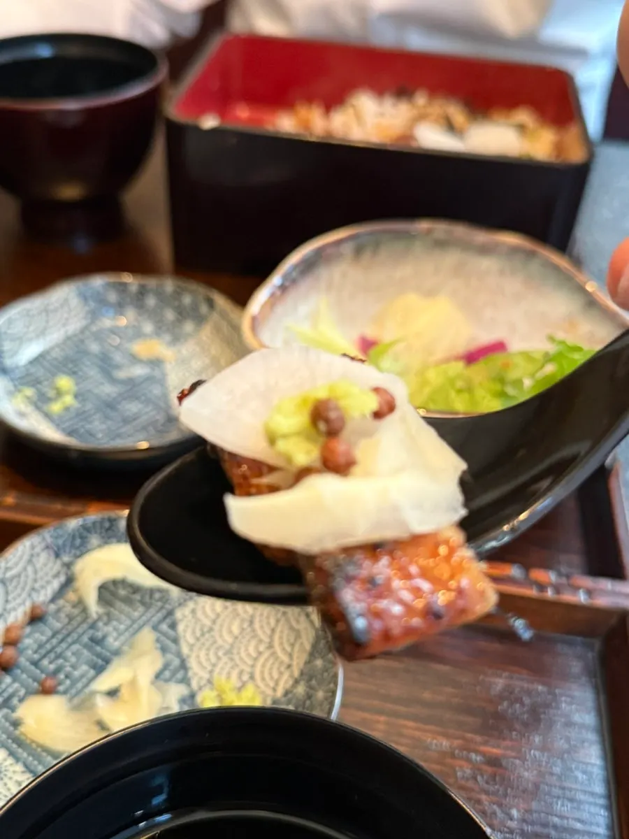 A bite of eel topped with pickled radish and wasabi