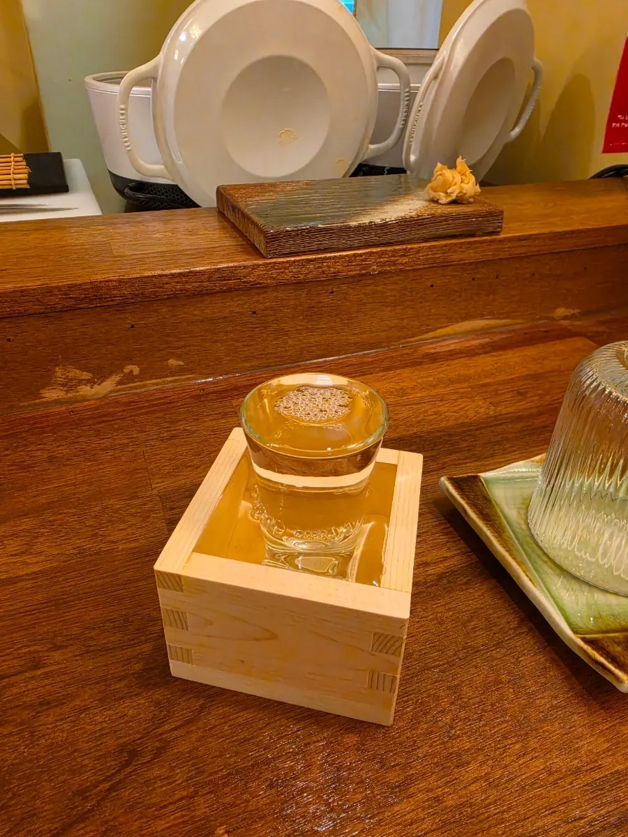 A glass of house sake poured to the brim