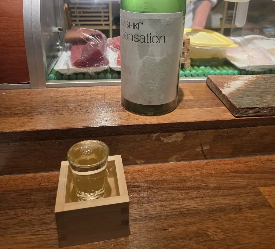 House sake Sensation White poured generously, overflowing the glass