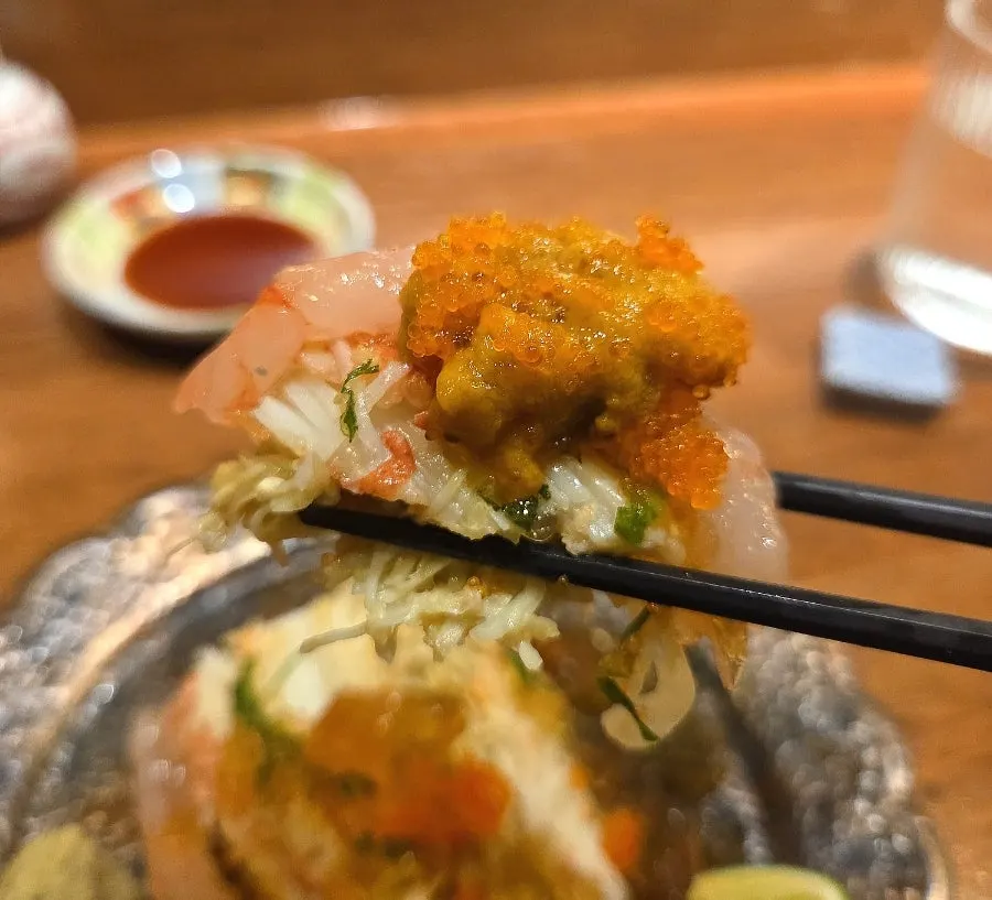 A single bite combining crab, uni, and sweet shrimp