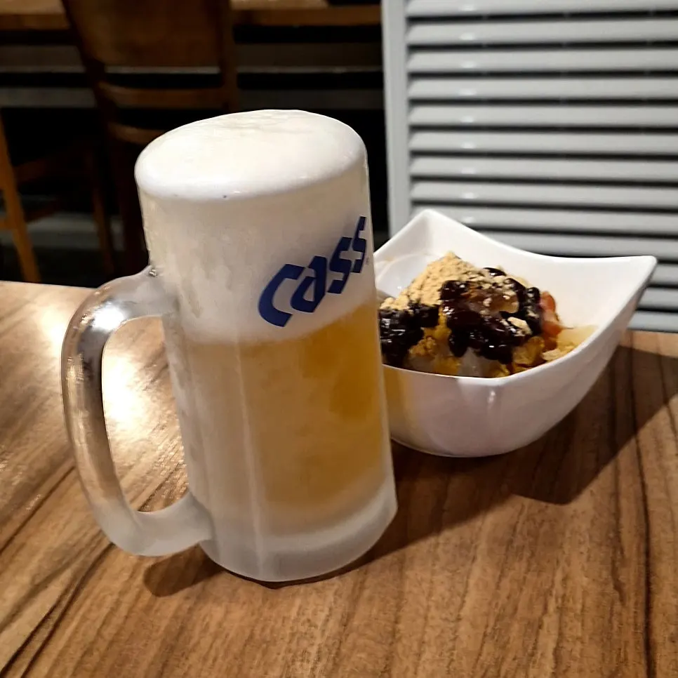 A glass of frosty draft beer with foam on top