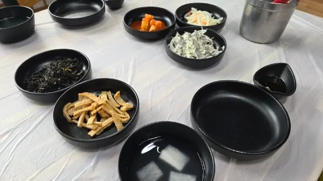 Table set with basic side dishes and ttukbaegi steamed egg