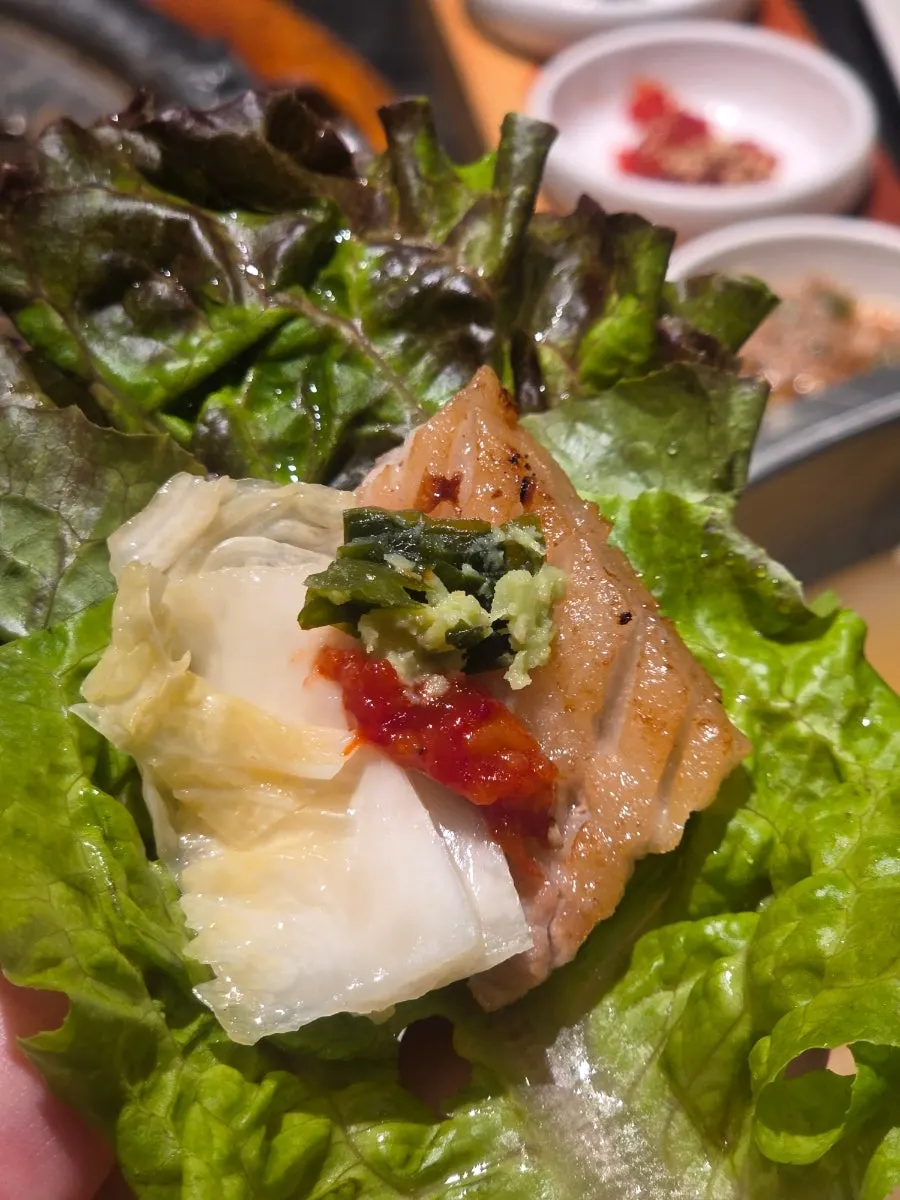 A piece of fresh rib topped with sauce and wrapped in lettuce