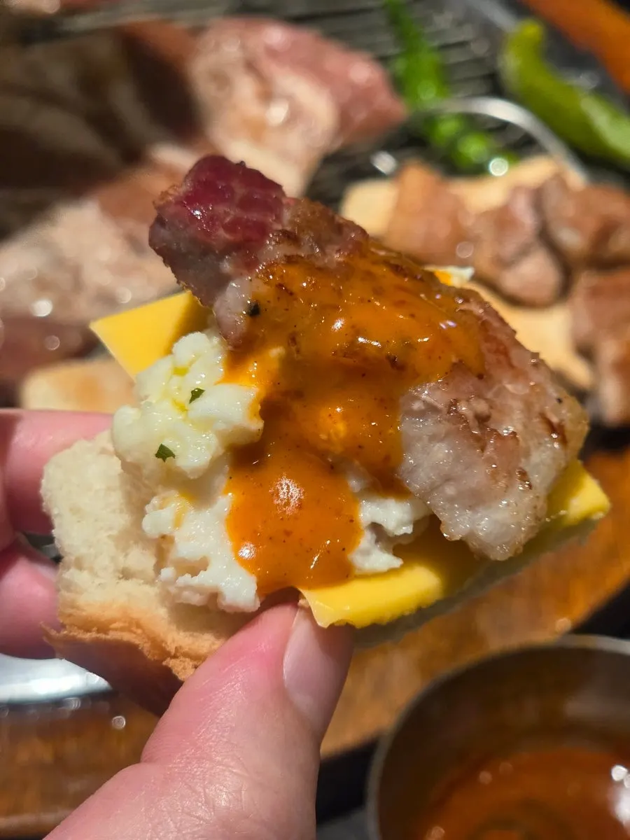 A bite of cheese toast topped with potato salad and marinated rib