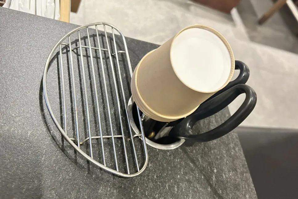 Table corner storage with tongs, scissors, and paper cups