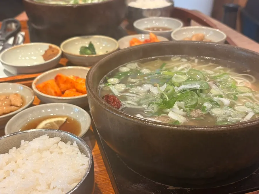 A full spread of Gang Galbitang's short rib soup served in a stone pot