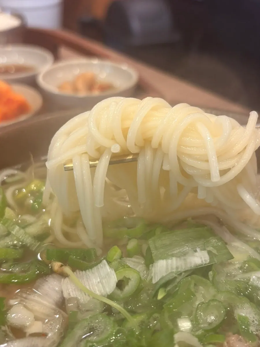 A spoonful of galbitang broth lifted from the bowl