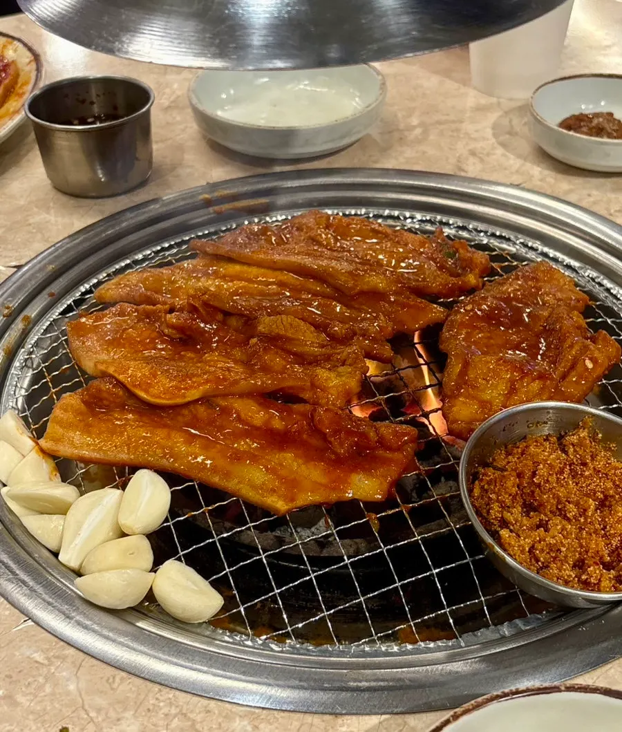 Gochujang samgyeopsal cooking on the grill