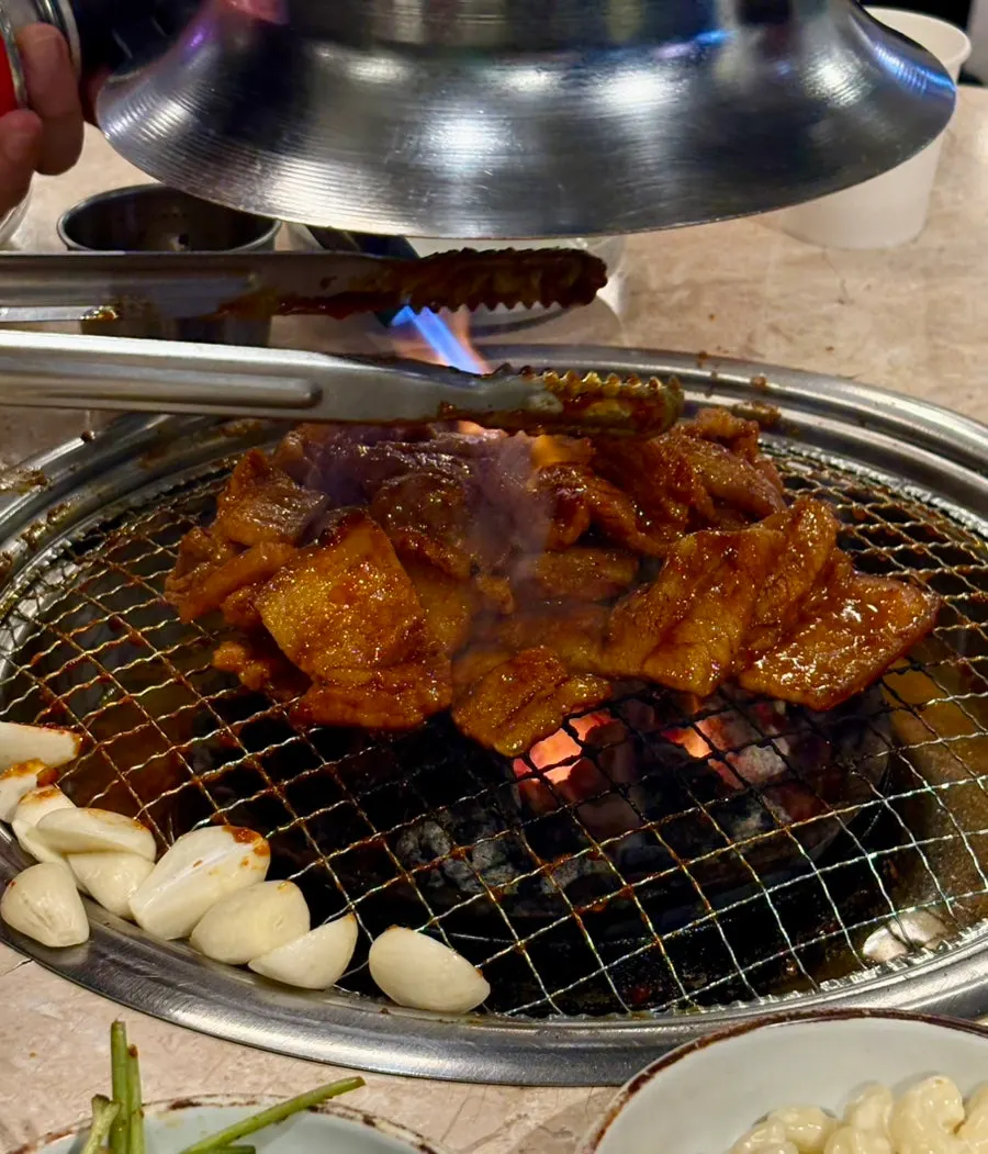 Seasoned pork belly grilling over charcoal