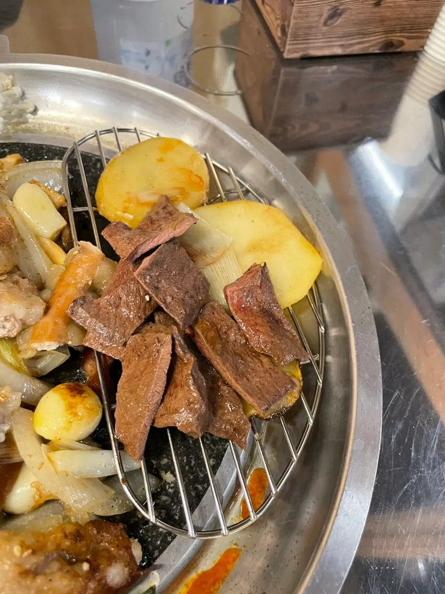 Mixing the cooked gopchang and vegetables on the grill