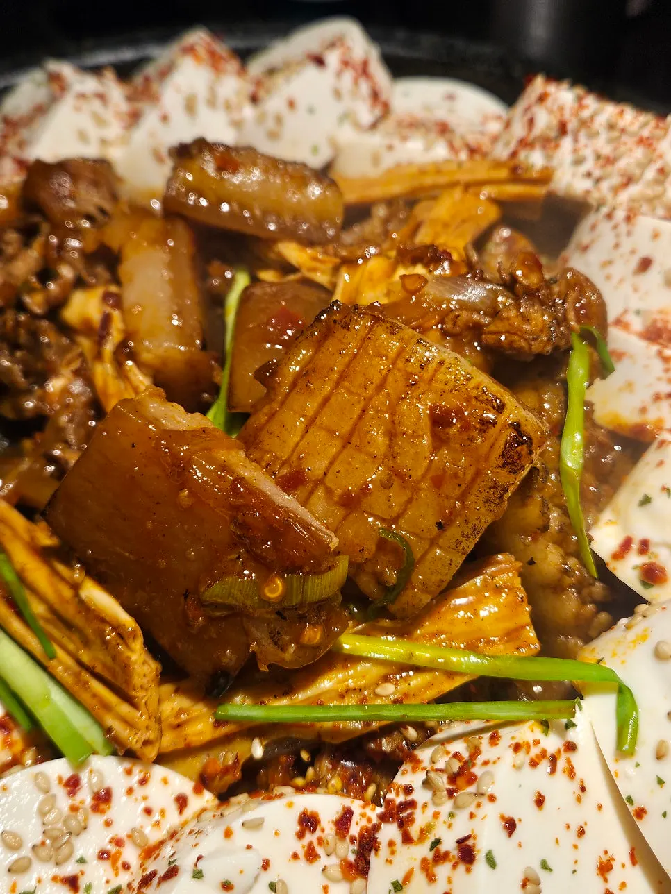 순두부 아래 껍데기와 푸주, 버섯이 보이는 뚝배기 속