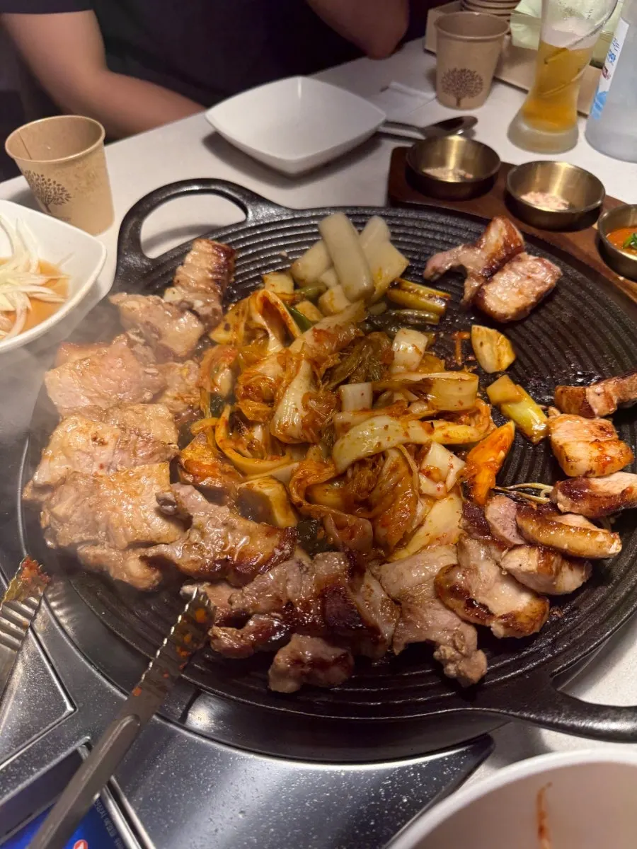 불판에서 김치, 떡, 버섯과 함께 익어가는 삼겹살