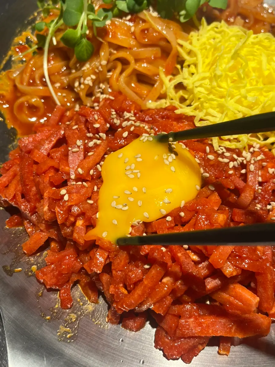 Mixing the yukhoe and bibim kalguksu with the sauce