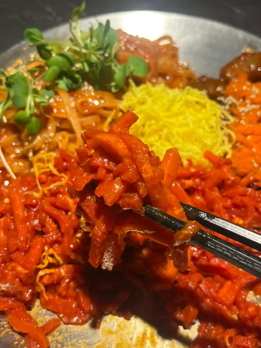 Chopsticks lifting a strand of bibim kalguksu noodles