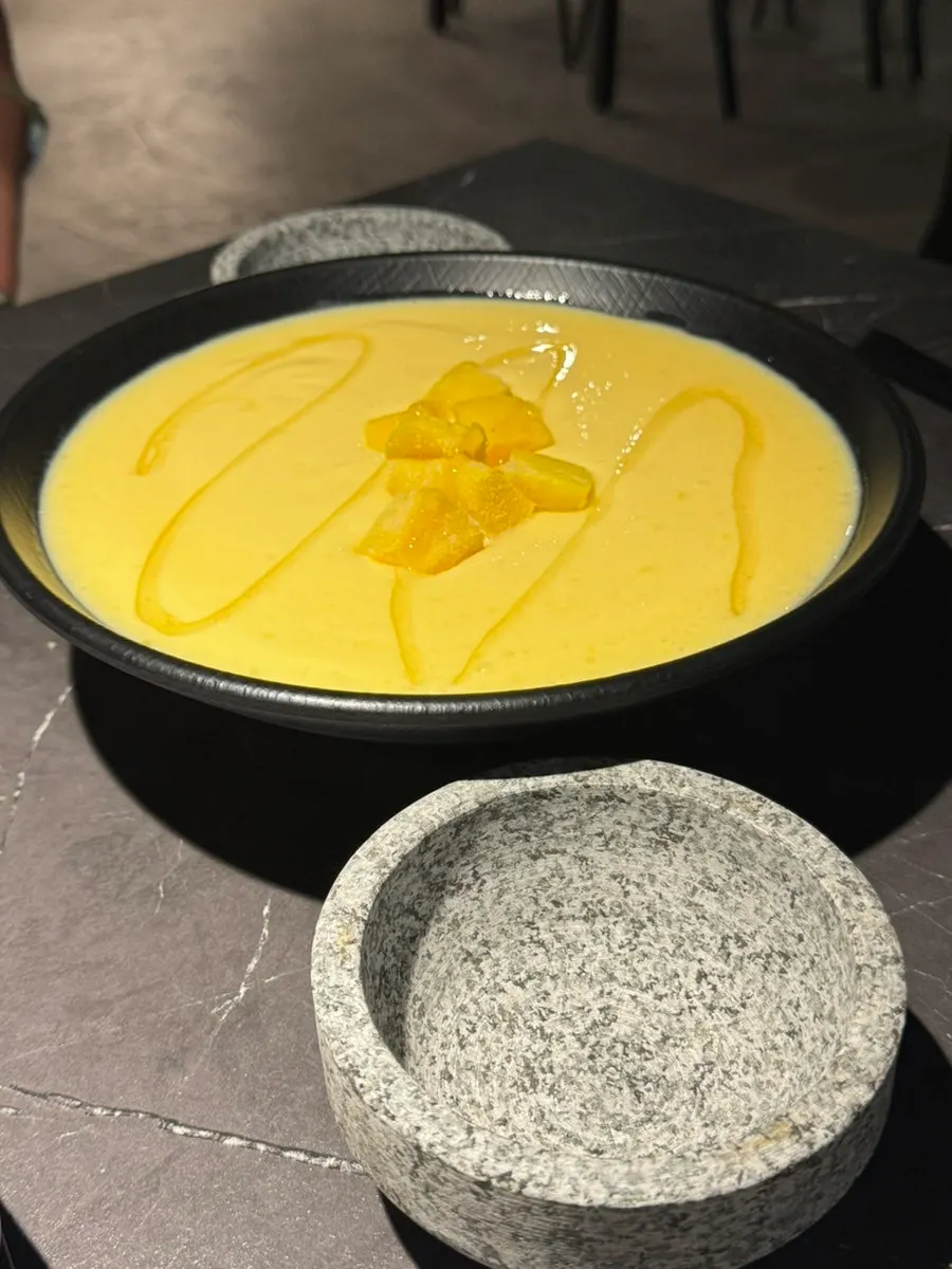 Honey mango makgeolli ladled into the small cup