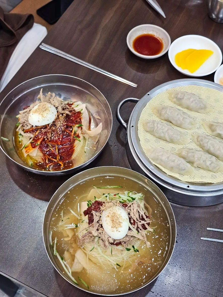 A table spread of mul-milmyeon, bibim-milmyeon, and dumplings at Seomyeon Milmyeon