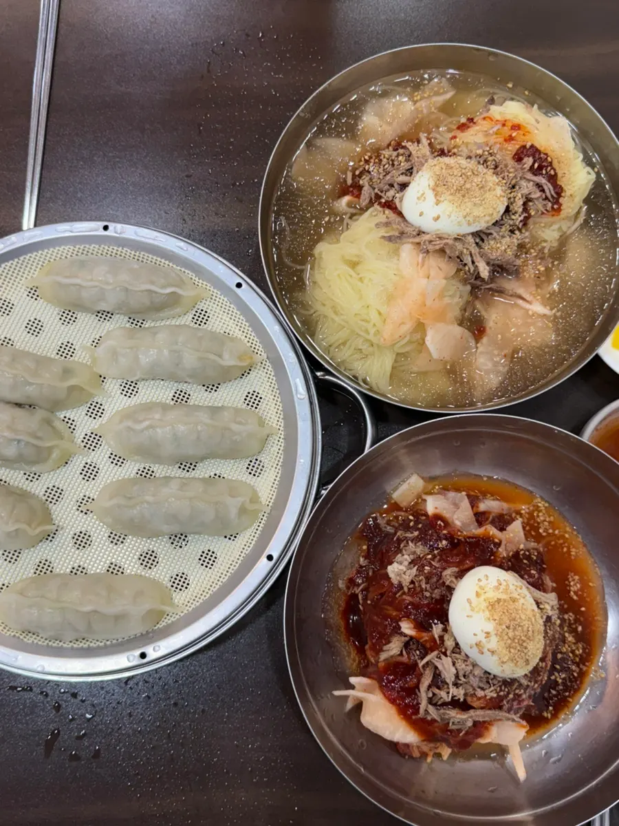 Table set with water milmyeon, bibim milmyeon, and dumplings