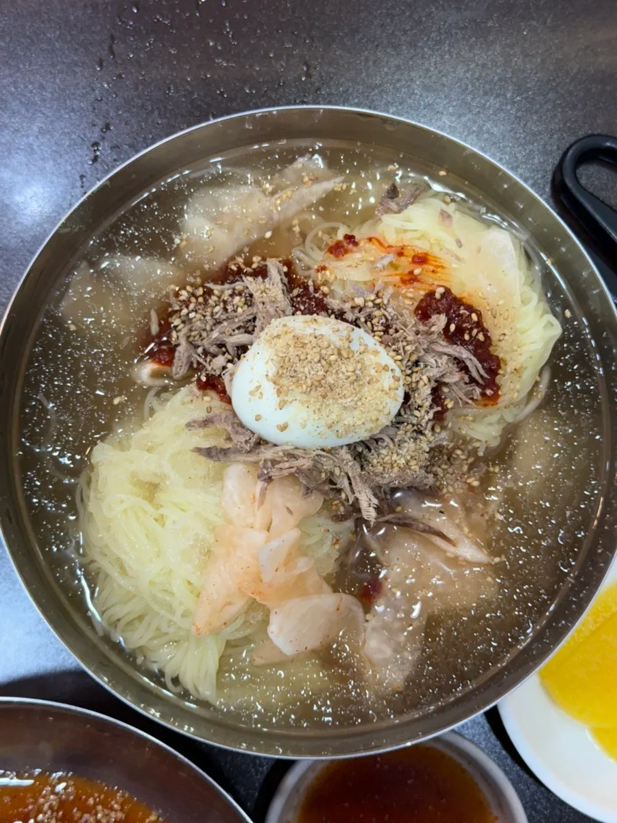 Water milmyeon with extra noodles and dumplings on the steamer