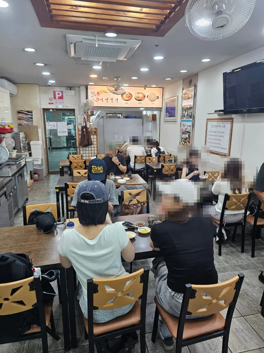 Interior of Seomyeon Milmyeon with wood-tone tables in a row