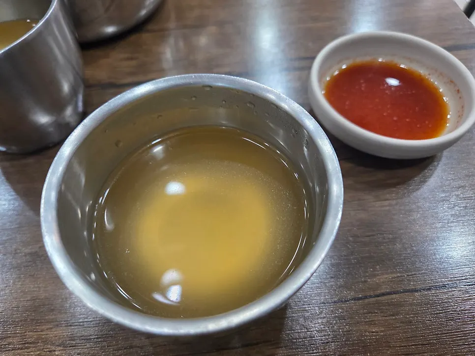 The free warm broth, pickled radish, and radish kimchi served at the start