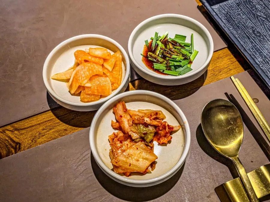 Basic side dishes of kimchi, pickled radish wraps, and seasoned chives