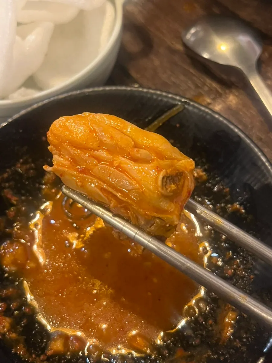 A moist piece of dakdoritang picked up with chopsticks