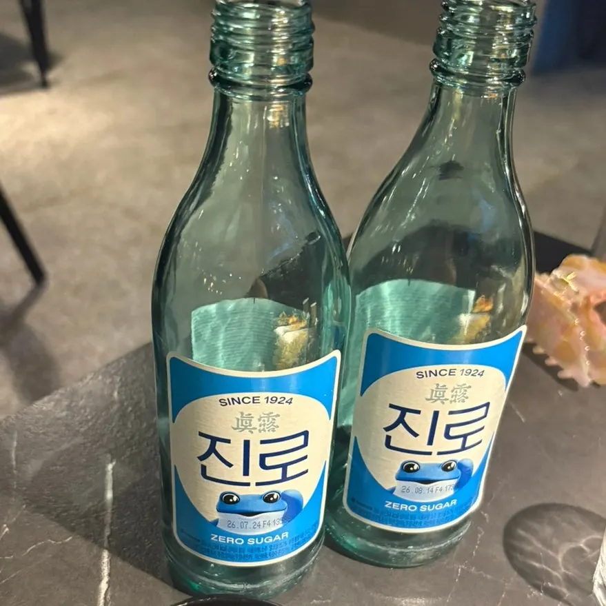 Pepperoni-topped pasta next to a soju glass