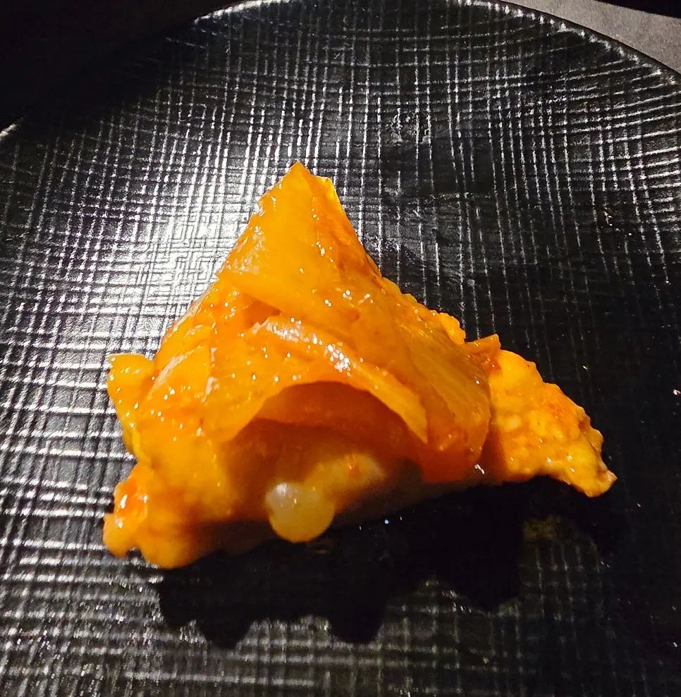 A piece of daechang wrapped in kimchi