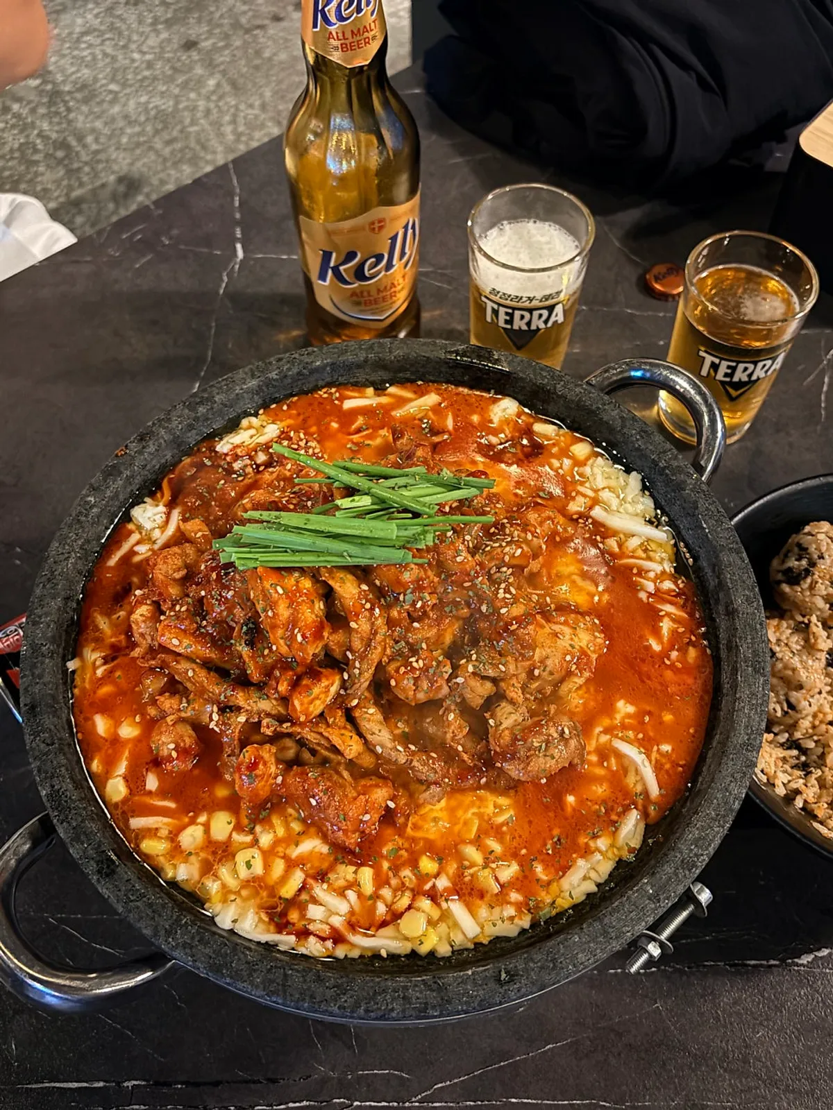 Hot stone plate with cheese and chicken neck meat over a gas burner