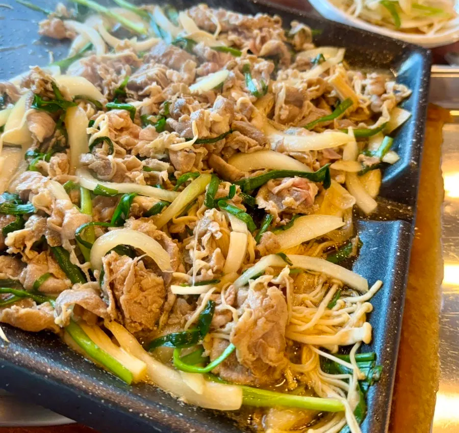 Duck bulgogi and vegetables piled high on the grill pan